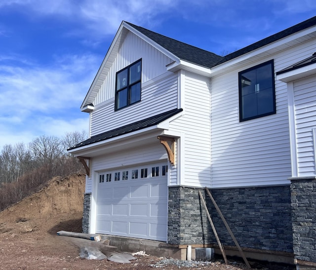 view of front of property with stone siding, roof with shingles, an attached garage, and board and batten siding