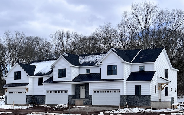 modern inspired farmhouse featuring an attached garage, a standing seam roof, and metal roof