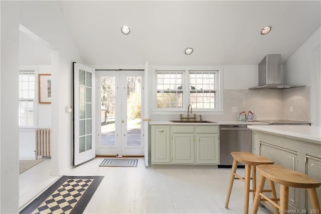 kitchen with sink, light wood-type flooring, french doors, wall chimney exhaust hood, and radiator heating unit