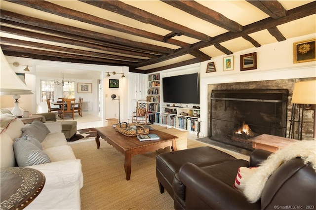 living room featuring beam ceiling, a chandelier, and built in shelves