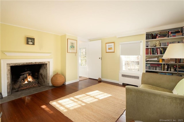 living room featuring crown molding, dark wood-type flooring, a fireplace, and radiator heating unit