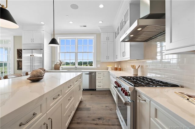 kitchen with decorative light fixtures, dark hardwood / wood-style floors, white cabinets, wall chimney range hood, and high quality appliances