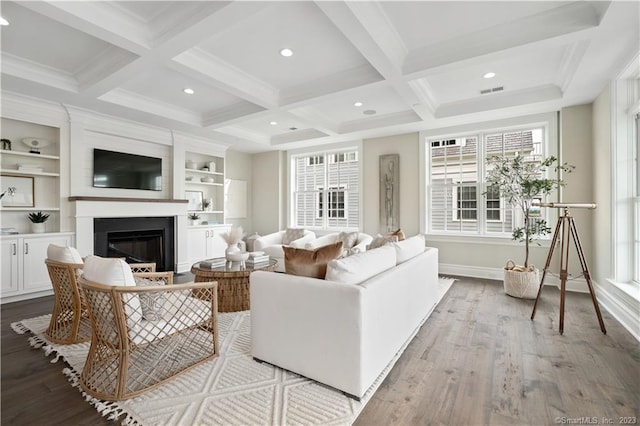 living room featuring coffered ceiling, built in features, light hardwood / wood-style floors, and beam ceiling