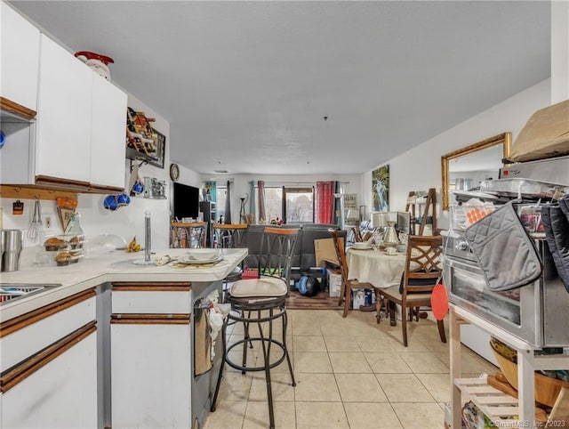 kitchen featuring white cabinetry, light tile floors, and a kitchen breakfast bar