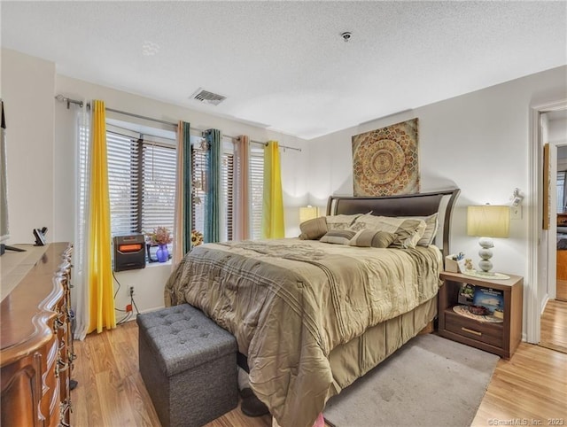 bedroom with light hardwood / wood-style floors and a textured ceiling