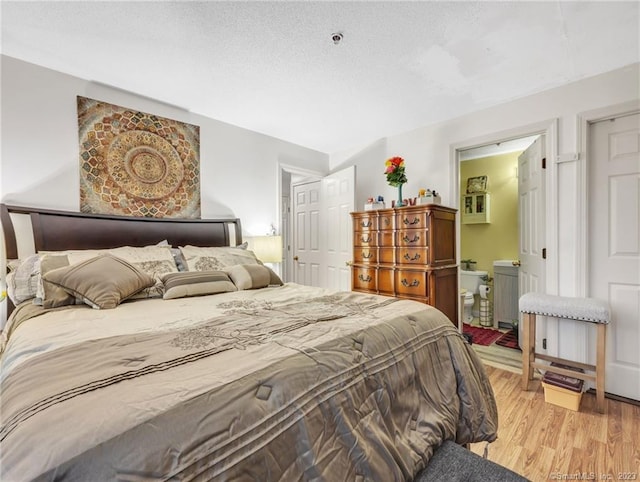 bedroom with ensuite bathroom and light wood-type flooring