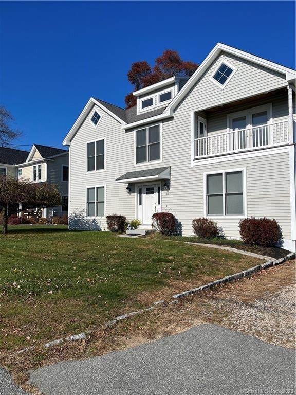 view of front of house featuring a balcony and a front lawn