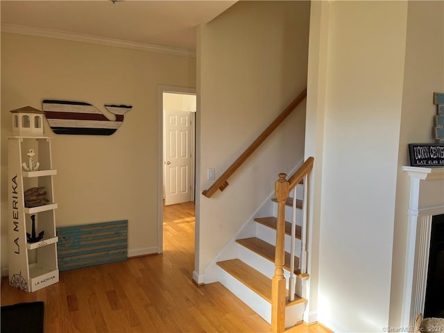 staircase featuring crown molding and light wood-type flooring