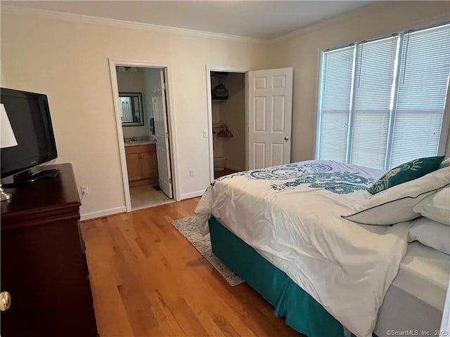 bedroom with light hardwood / wood-style floors, connected bathroom, ornamental molding, and multiple windows