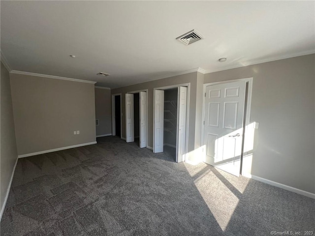 empty room featuring dark colored carpet and crown molding