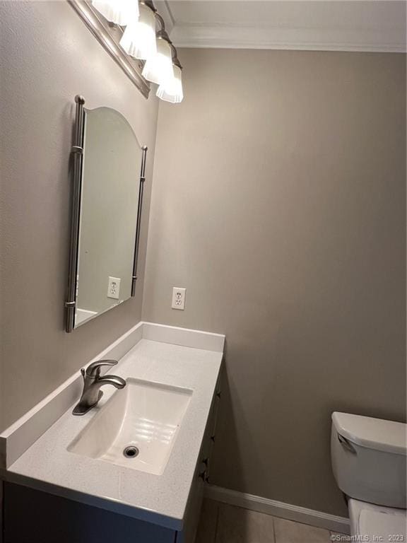 bathroom with toilet, ornamental molding, tile floors, and vanity with extensive cabinet space