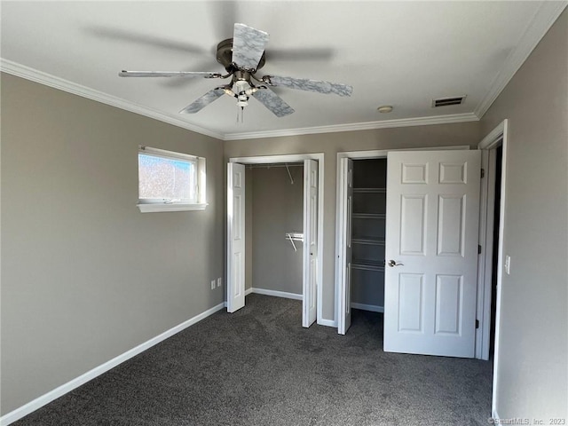 unfurnished bedroom with multiple closets, ceiling fan, ornamental molding, and dark carpet