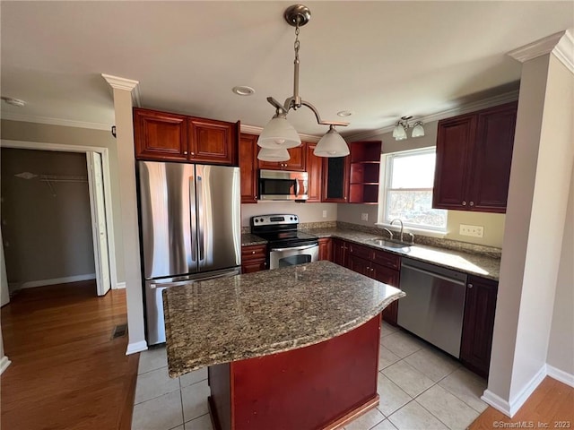 kitchen featuring pendant lighting, light hardwood / wood-style floors, a kitchen island, appliances with stainless steel finishes, and sink