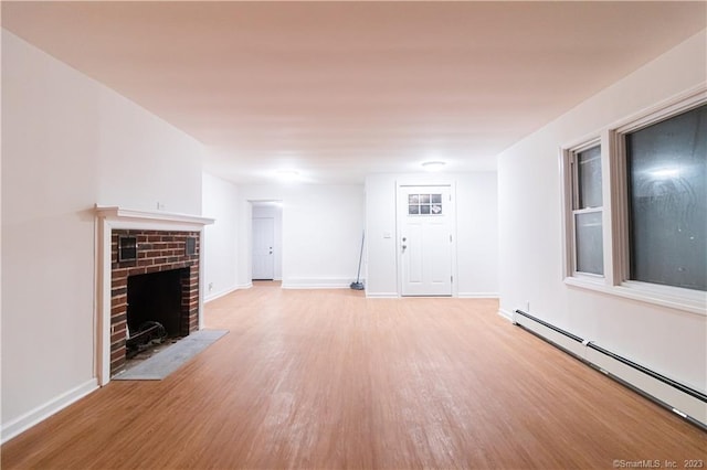 unfurnished living room featuring a fireplace, a baseboard radiator, and light hardwood / wood-style flooring