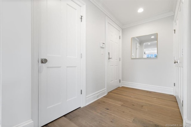 corridor with light hardwood / wood-style floors and ornamental molding