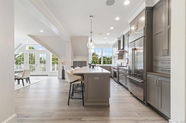 66 High St Unit 55, Guilford, CT 06437 - kitchen featuring high quality appliances, gray cabinetry, a center island, a breakfast bar, and wall chimney exhaust hood