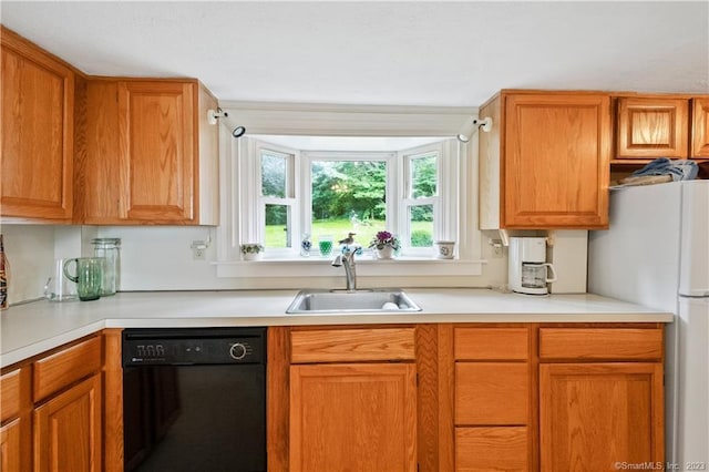 kitchen featuring light countertops, freestanding refrigerator, a sink, and black dishwasher