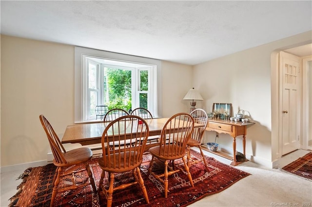 carpeted dining area featuring baseboards