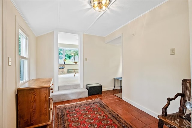interior space with lofted ceiling, tile patterned flooring, baseboards, and ornamental molding
