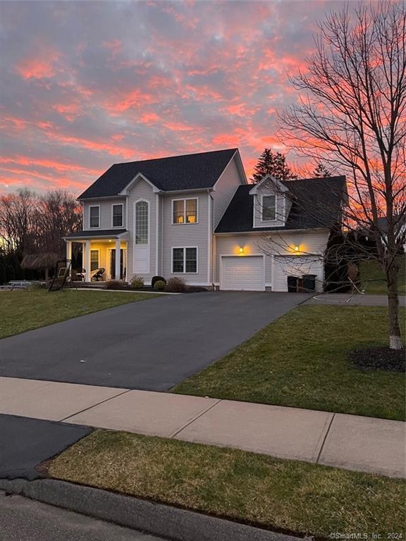 view of front of house with a yard, a garage, and a porch