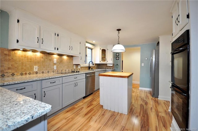 kitchen featuring wooden counters, light hardwood / wood-style flooring, backsplash, a center island, and black appliances