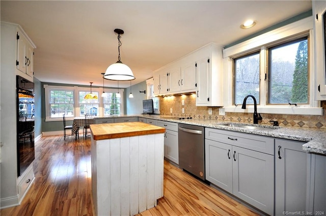 kitchen featuring wooden counters, sink, light wood-type flooring, a center island, and dishwasher