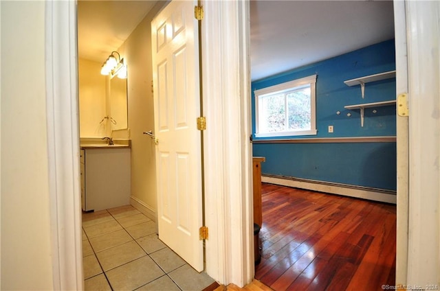 hall featuring a baseboard radiator, light tile patterned floors, and sink