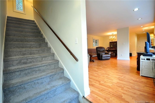 stairway featuring a notable chandelier and wood-type flooring