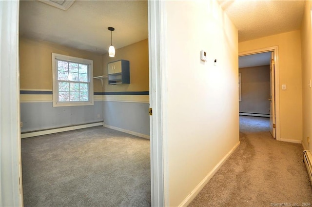 hallway with a baseboard heating unit and carpet floors