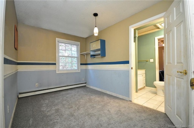 tiled empty room featuring a baseboard radiator and a textured ceiling