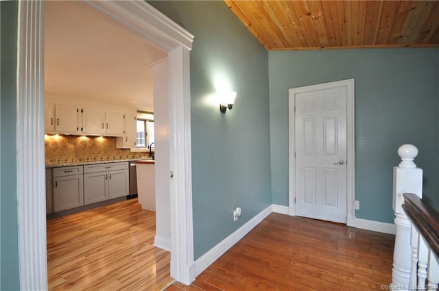 hallway featuring lofted ceiling, sink, light wood-type flooring, and wooden ceiling