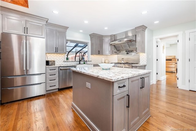 kitchen featuring appliances with stainless steel finishes, gray cabinetry, light hardwood / wood-style flooring, and a kitchen island