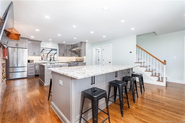 kitchen featuring gray cabinetry, a spacious island, light hardwood / wood-style floors, and stainless steel fridge