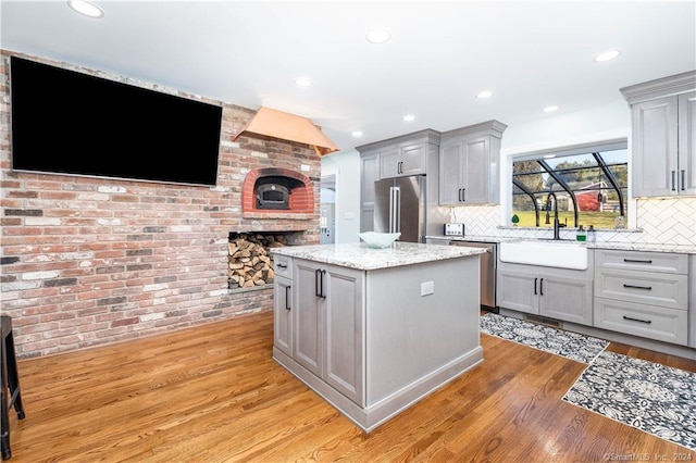 kitchen with gray cabinetry, appliances with stainless steel finishes, and a brick fireplace