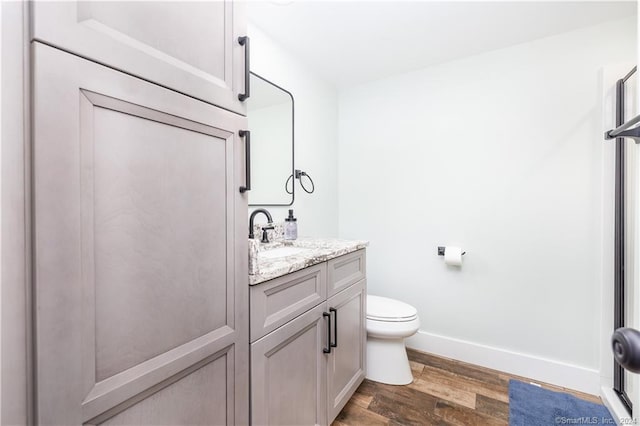 bathroom with toilet, vanity, and hardwood / wood-style flooring