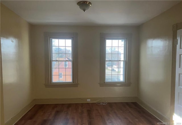 empty room with a healthy amount of sunlight and dark wood-type flooring