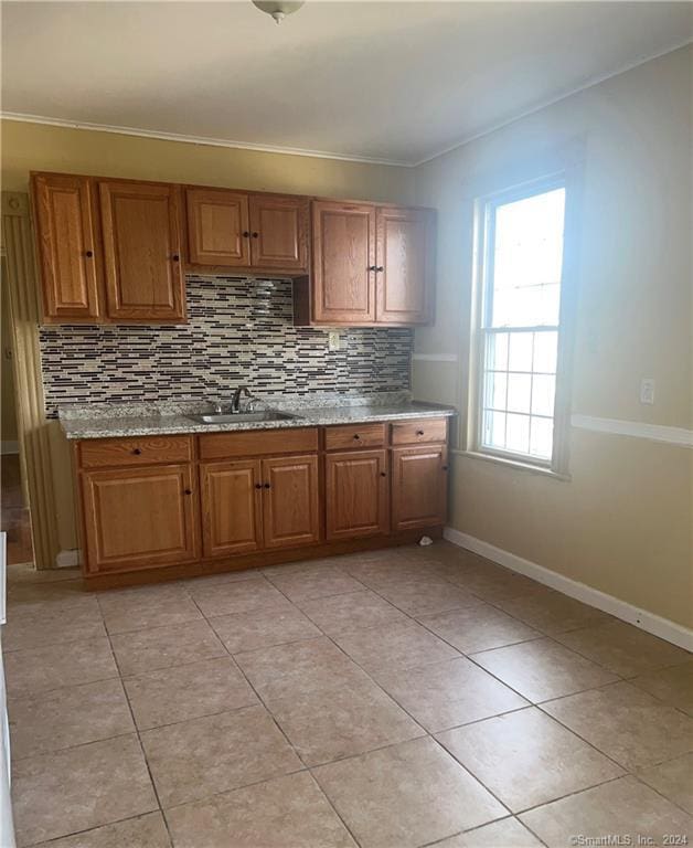 kitchen with sink, light stone countertops, tasteful backsplash, and light tile flooring