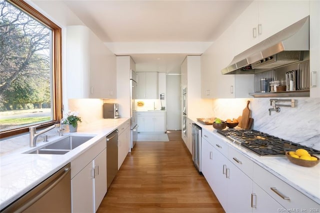 kitchen featuring light hardwood / wood-style flooring, appliances with stainless steel finishes, white cabinets, backsplash, and sink