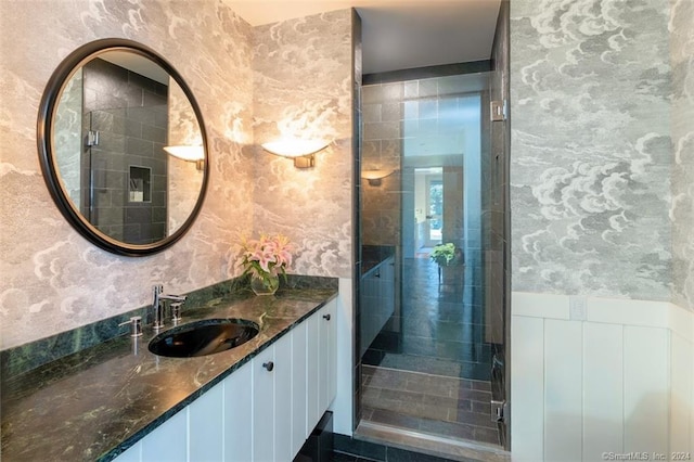 bathroom featuring a shower with door, tile floors, and vanity