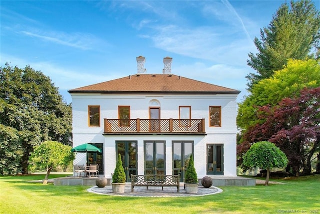 rear view of property with a balcony, a lawn, a patio, and french doors