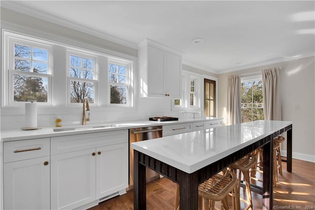 kitchen with dark hardwood / wood-style flooring, sink, ornamental molding, and white cabinets