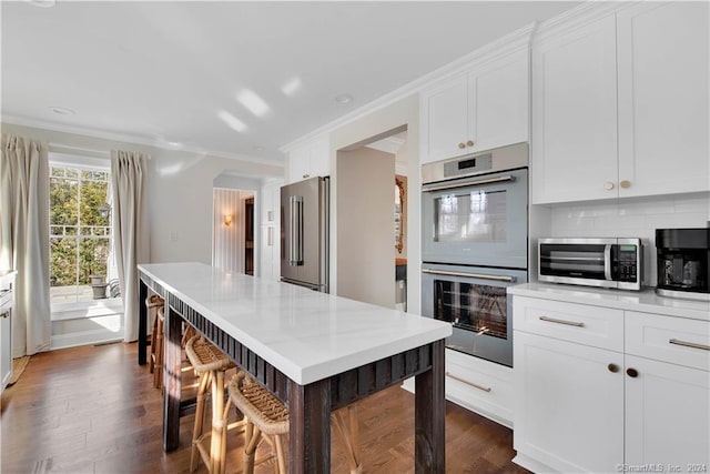 kitchen featuring backsplash, dark hardwood / wood-style floors, white cabinetry, and appliances with stainless steel finishes