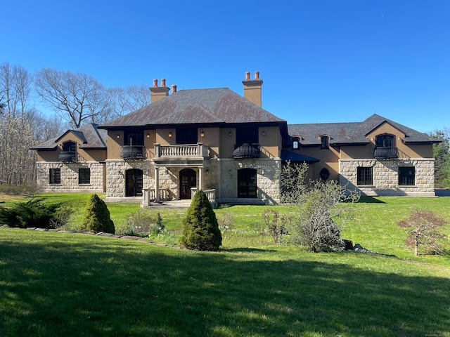 view of front of home featuring a balcony and a front yard