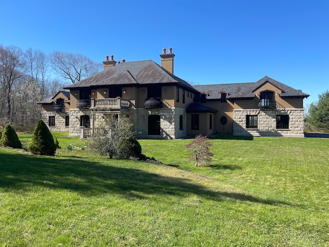 rear view of property featuring a yard and a balcony