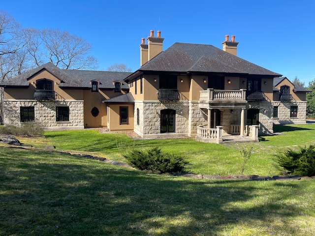 rear view of property with a balcony and a lawn