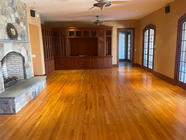 unfurnished living room featuring light hardwood / wood-style flooring, ceiling fan, and a fireplace