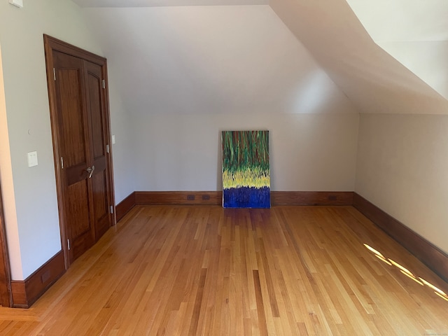 additional living space featuring lofted ceiling and light hardwood / wood-style flooring