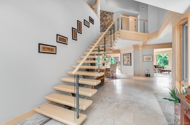 stairway with a towering ceiling and light tile flooring