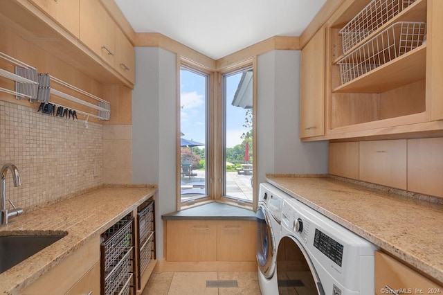 washroom with washing machine and clothes dryer, cabinets, sink, and light tile floors