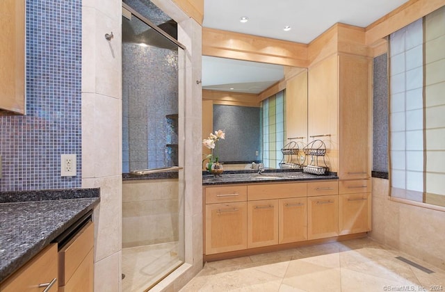 bathroom with tile flooring, tiled shower, and vanity with extensive cabinet space